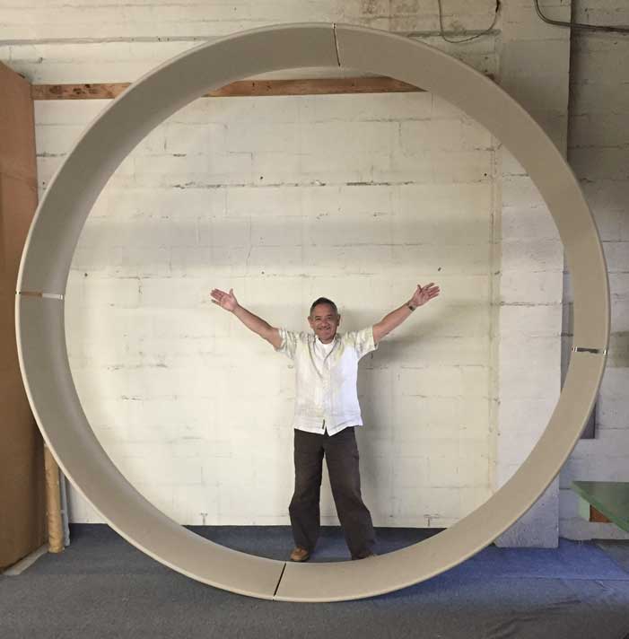A man standing in front of an object that is shaped like a circle.