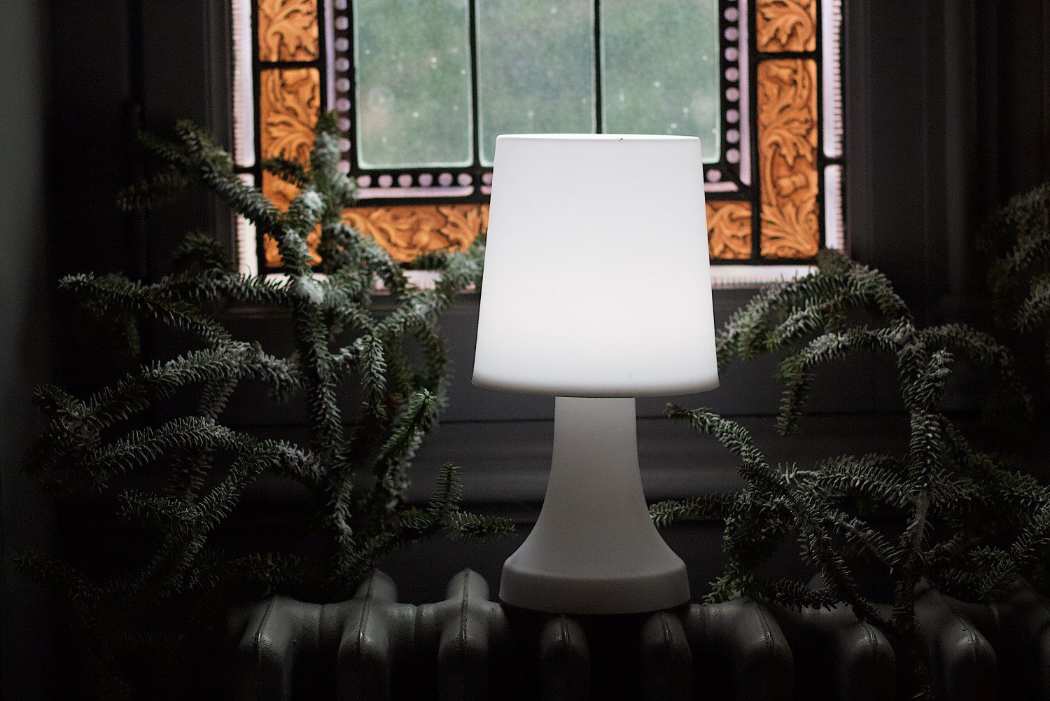 A white lamp sitting in front of a window.